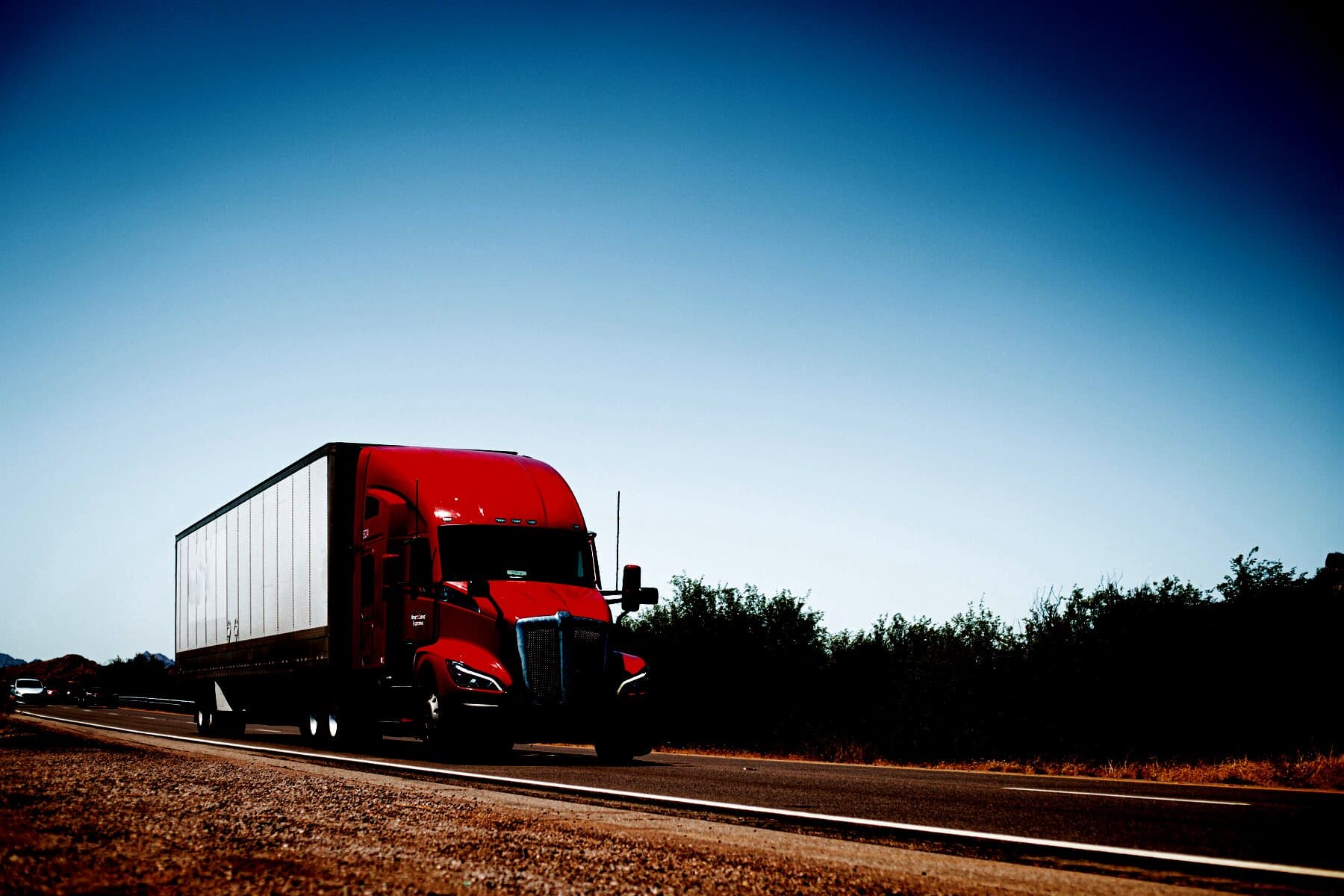A loaded tractor-trailer running a desert interstate